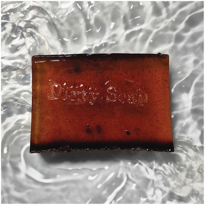 Dark Brown soap bar infused with coffee beans and stamped with a dirty soap logo 