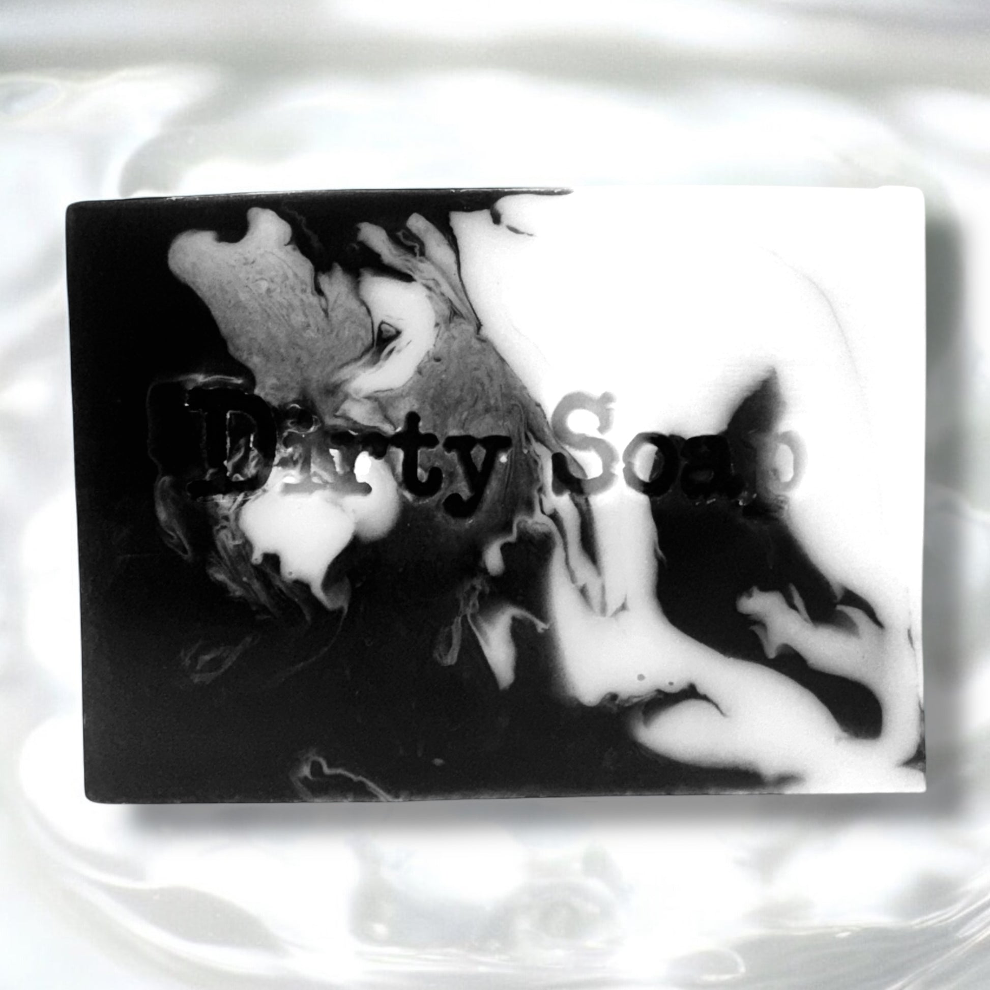 Black and white swirled soap bar sat on a bed of water with a dirty soap stamp